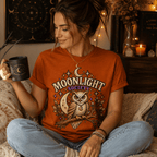 A woman wearing a burnt orange Moonlight Society cute celestial graphic t-shirt drinking coffee.