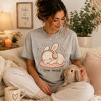 A woman wearing an athletic heather Low Noise Bunny graphic t-shirt petting bunny.