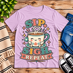 Sip. Sigh. Repeat. coffee graphic t-shirt cozy flat lay in lilac.