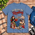 A cozy flat lay mockup of I'd Rather Be retro book graphic t-shirt in steel blue.