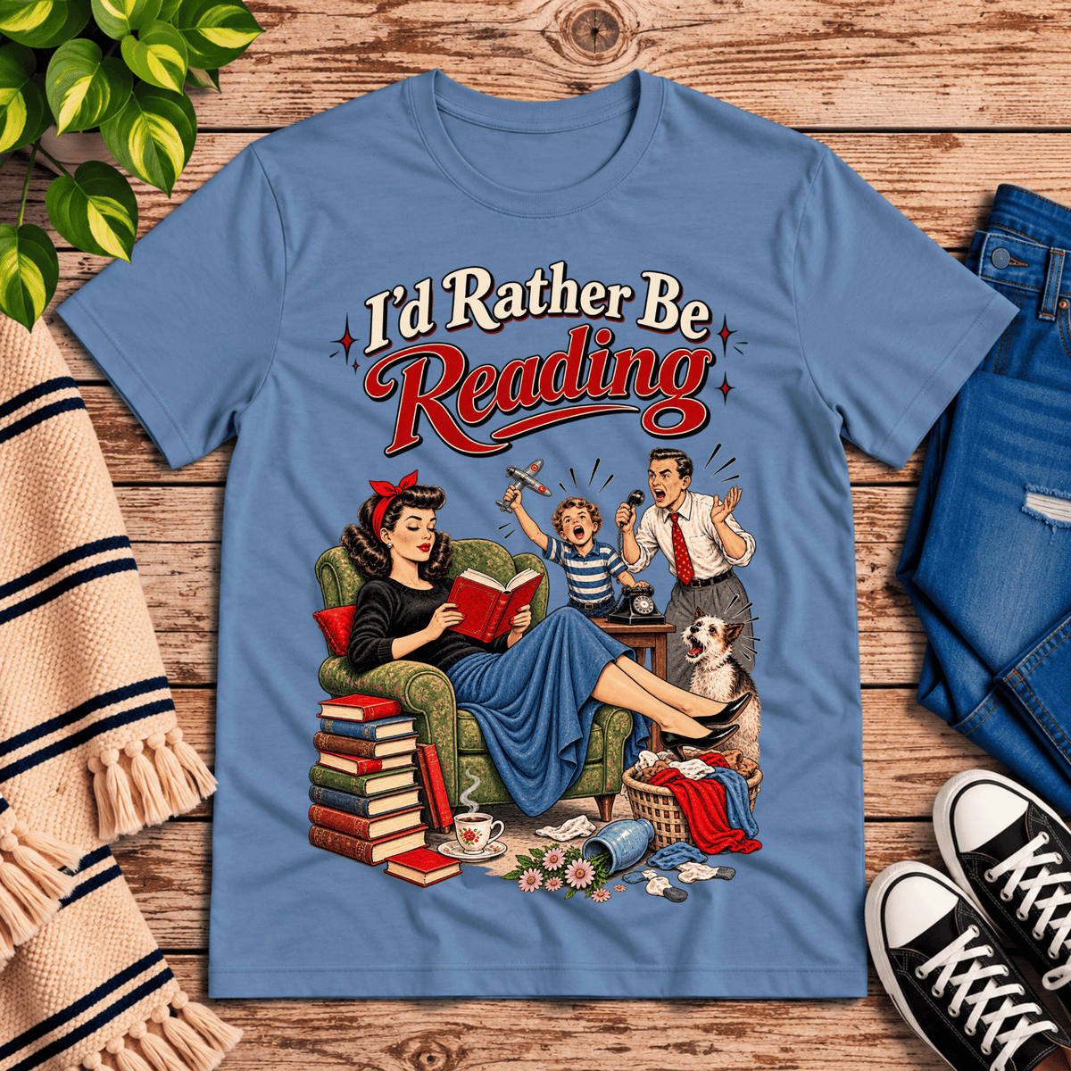 A cozy flat lay mockup of I'd Rather Be retro book graphic t-shirt in steel blue.