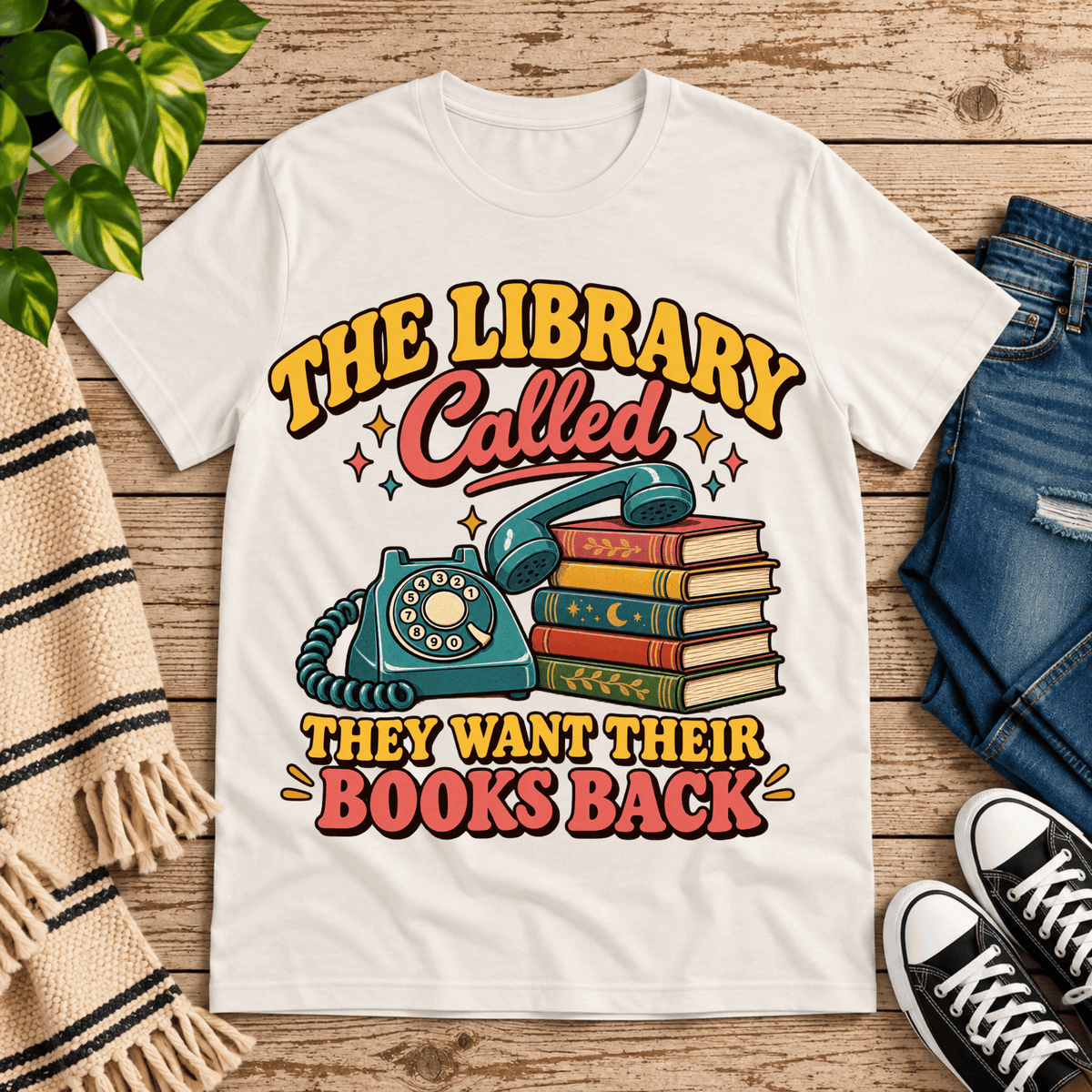 The Library Called book lovers graphic t-shirt cozy flat lay in vintage white.