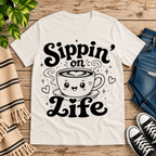 Sippin' on Life cute coffee graphic t-shirt cozy flat lay in vintage white.