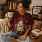 Woman on a couch wearing the All Nighter Premium T-Shirt in maroon, holding a coffee mug