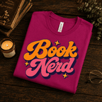 Book Nerd Premium T-Shirt in berry, folded close-up styled with vintage books and a candle