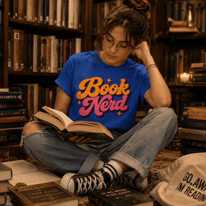 Woman reading on a rug wearing the Book Nerd Premium T-Shirt in true royal blue, surrounded by stacked books