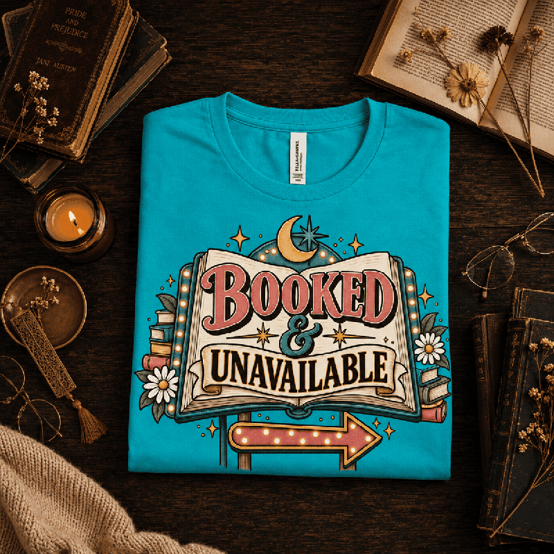 Booked & Unavailable Premium T-Shirt in heather sea green, folded close-up styled with vintage books and a candle