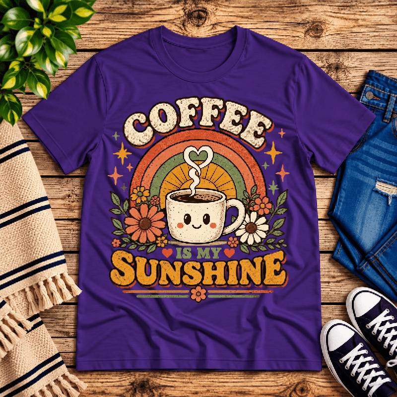 Coffee Is My Sunshine Premium T-Shirt in team purple, flat lay with smiling coffee cup, rainbow, and floral graphic