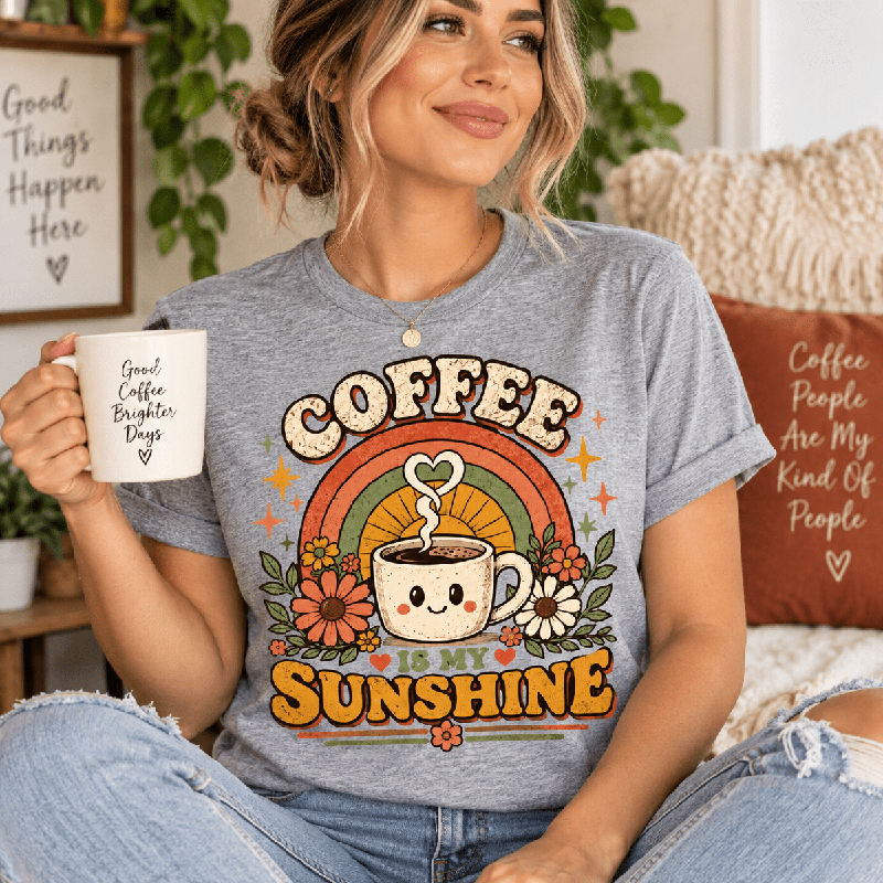 Woman holding a mug, wearing the Coffee Is My Sunshine Premium T-Shirt in athletic heather gray