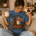 Woman holding a mug, wearing the Currently Avoiding Premium T-Shirt in steel blue