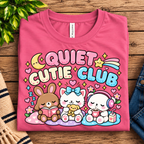A folded mockup of Quiet Cutie Club cute animal graphic t-shirt in charity pink.