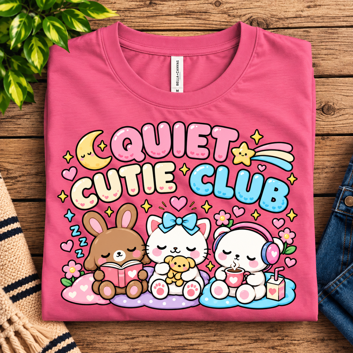 A folded mockup of Quiet Cutie Club cute animal graphic t-shirt in charity pink.