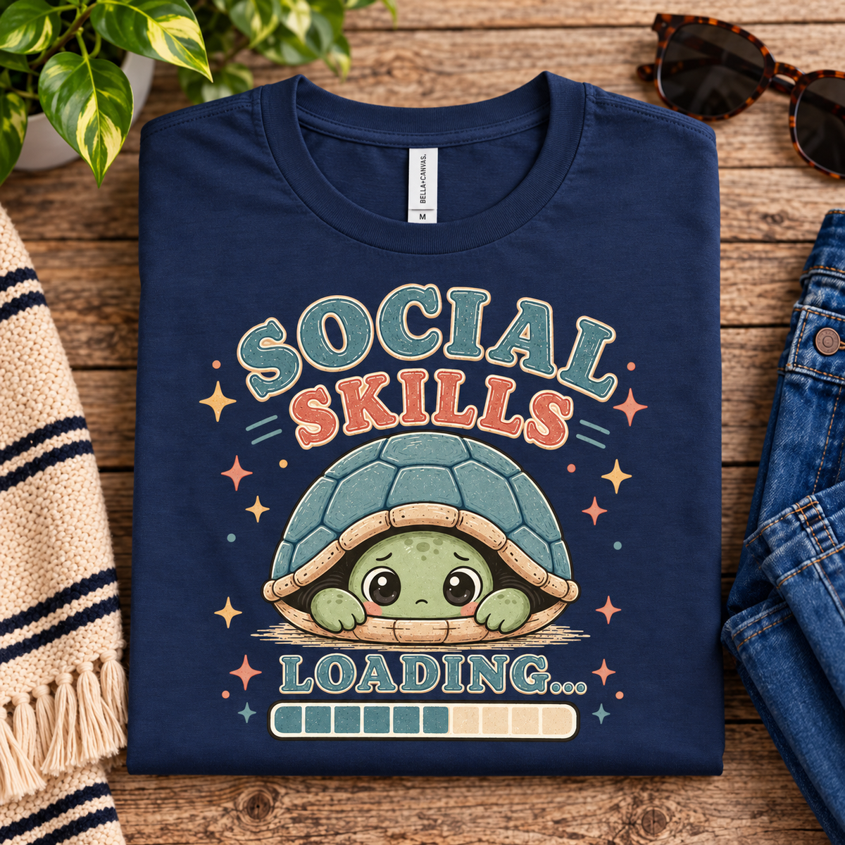 A folded mockup of Social Skills cute animal graphic t-shirt in deep teal.