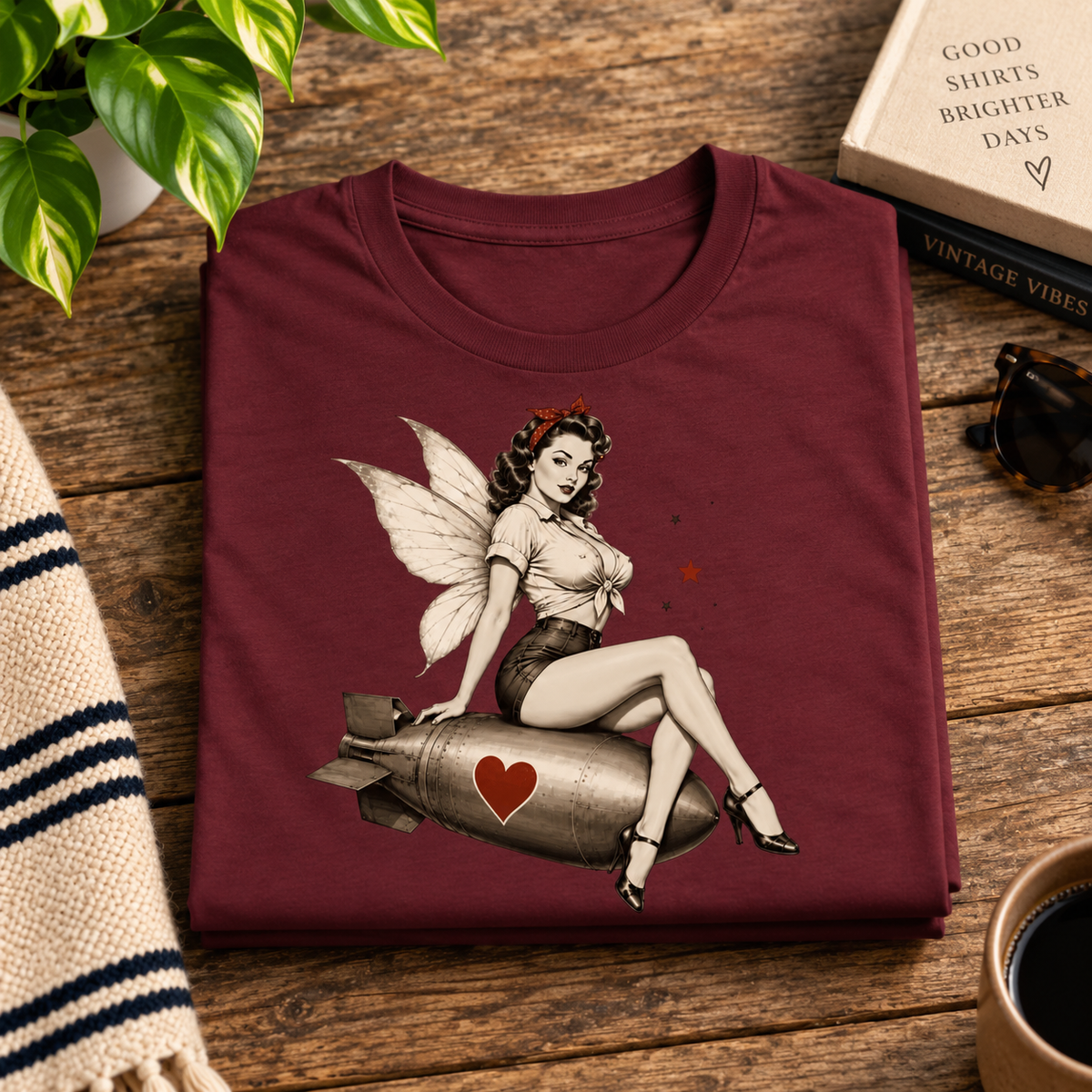 A folded mockup of Love Bomb vintage pinup graphic t-shirt in maroon.