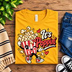 A folded mockup of It's Poppin' retro food graphic t-shirt in gold.
