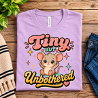 A folded mockup of Tiny but Unbothered cute animal graphic t-shirt in lilac.