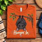 A folded mockup of Hangin' In cute introvert graphic t-shirt in burnt orange.