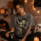 Woman wearing the Frankie & Frannie Premium T-Shirt in asphalt gray, seated with Halloween decor and a mug