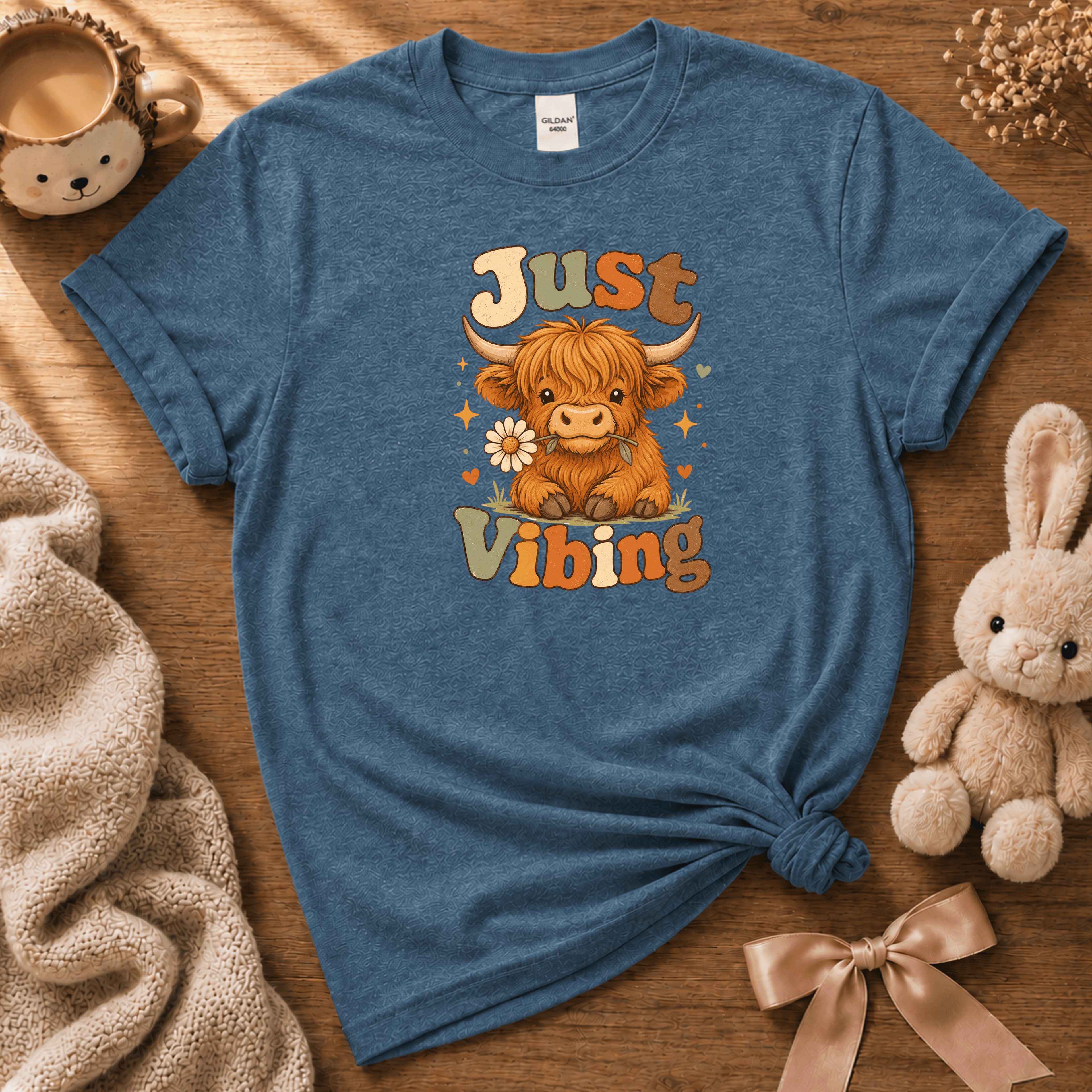 Just Vibing Cow cute animal graphic t-shirt displayed in a cozy flat lay in indigo blue.