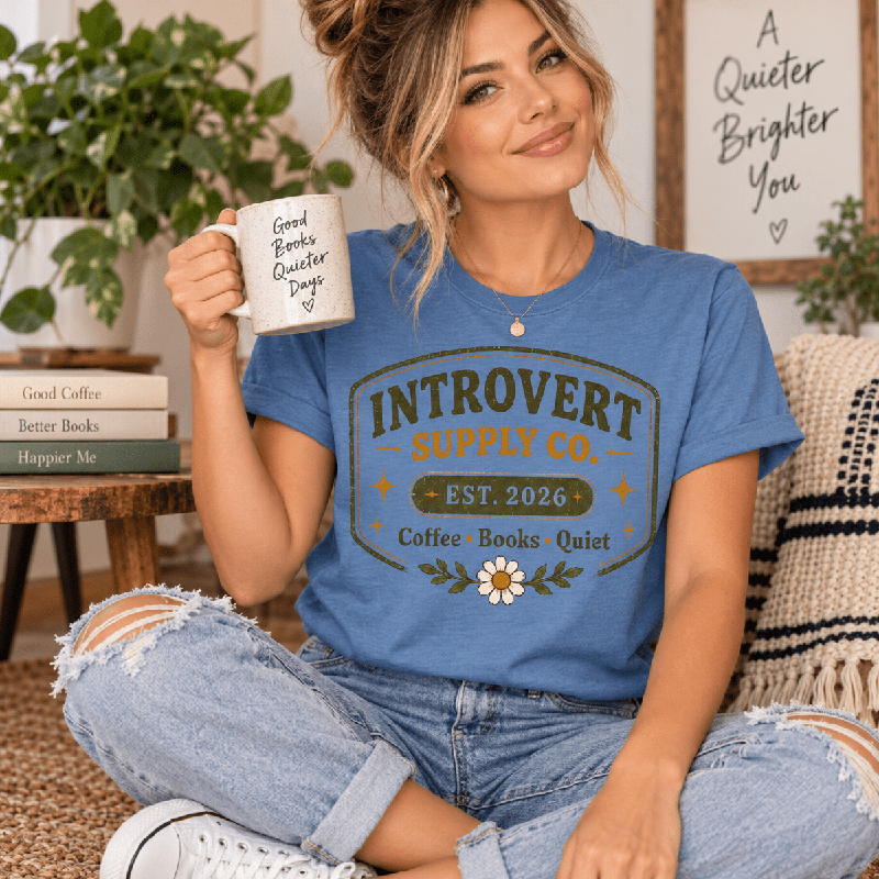 Woman holding a "Good Books Quieter Days" mug, wearing the Introvert Supply Co. Premium T-Shirt in steel blue