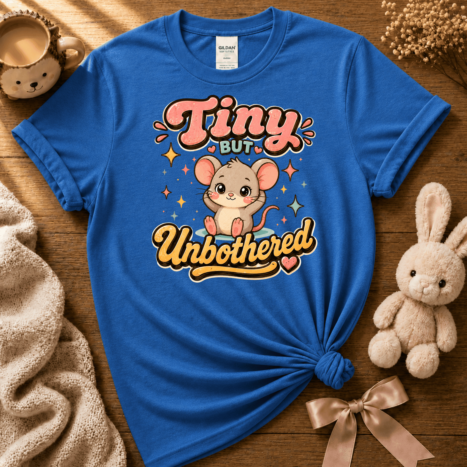 Tiny But Unbothered cute animal graphic t-shirt displayed in a cozy flat lay in iris blue.