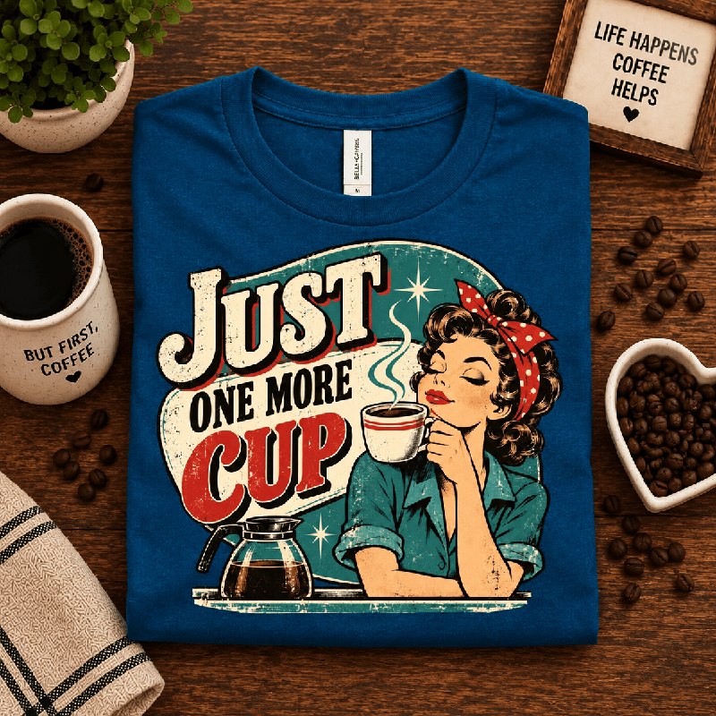 Just One More Premium T-Shirt in deep teal, folded close-up styled with coffee props