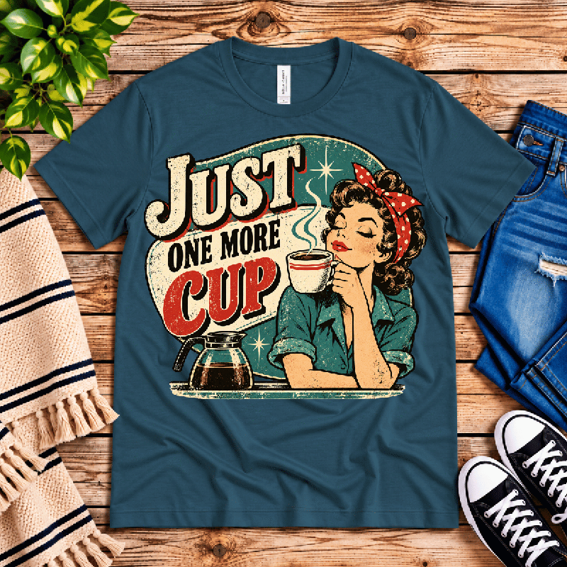 Just One More Premium T-Shirt in deep teal, flat lay with retro pin-up coffee graphic and "Just One More Cup" text