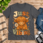 Just Vibing Cow Premium T-Shirt in asphalt gray, flat lay with Highland cow holding a daisy graphic