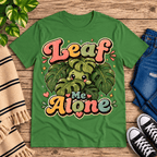 Leaf Me Alone Premium T-Shirt in leaf green, flat lay with cartoon leaf character peeking from monstera leaves graphic