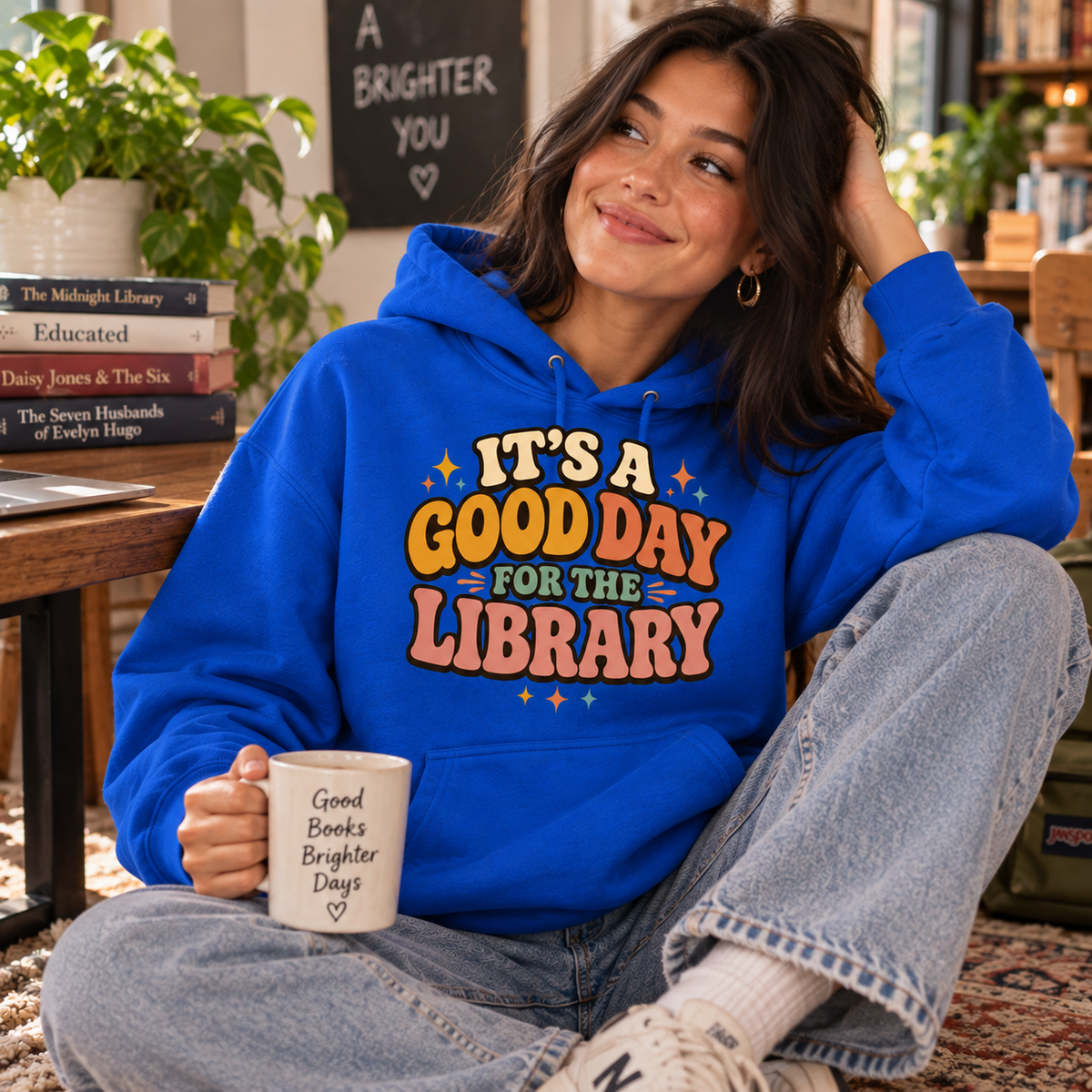 A woman wearing a royal blue It's A Good Day cute book graphic hoodie.