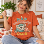 A woman wearing a burnt orange Nap Enthusiasts Club cute animal graphic t-shirt.