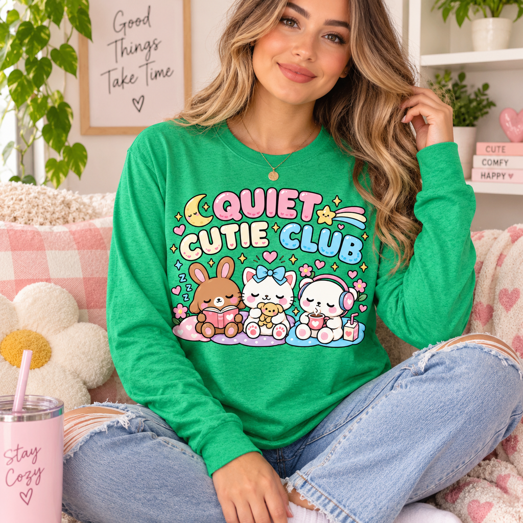 A woman wearing a retro heather green Quiet Cutie Club introvert graphic long sleeve.