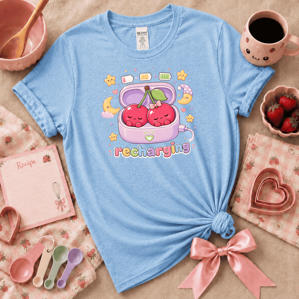 Recharging Cherries kawaii cute fruit graphic t-shirt displayed in a cozy flat lay in light blue.