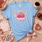 Recharging Cherries kawaii cute fruit graphic t-shirt displayed in a cozy flat lay in light blue.