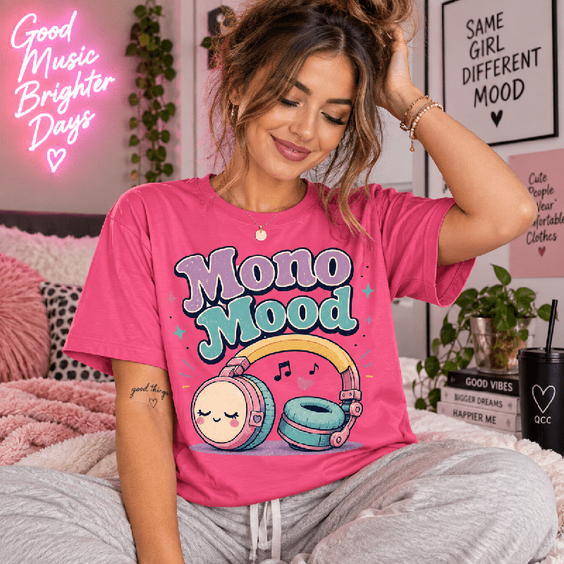 Woman sitting on a bed near neon wall art, wearing the Mono Mood Premium T-Shirt in charity pink