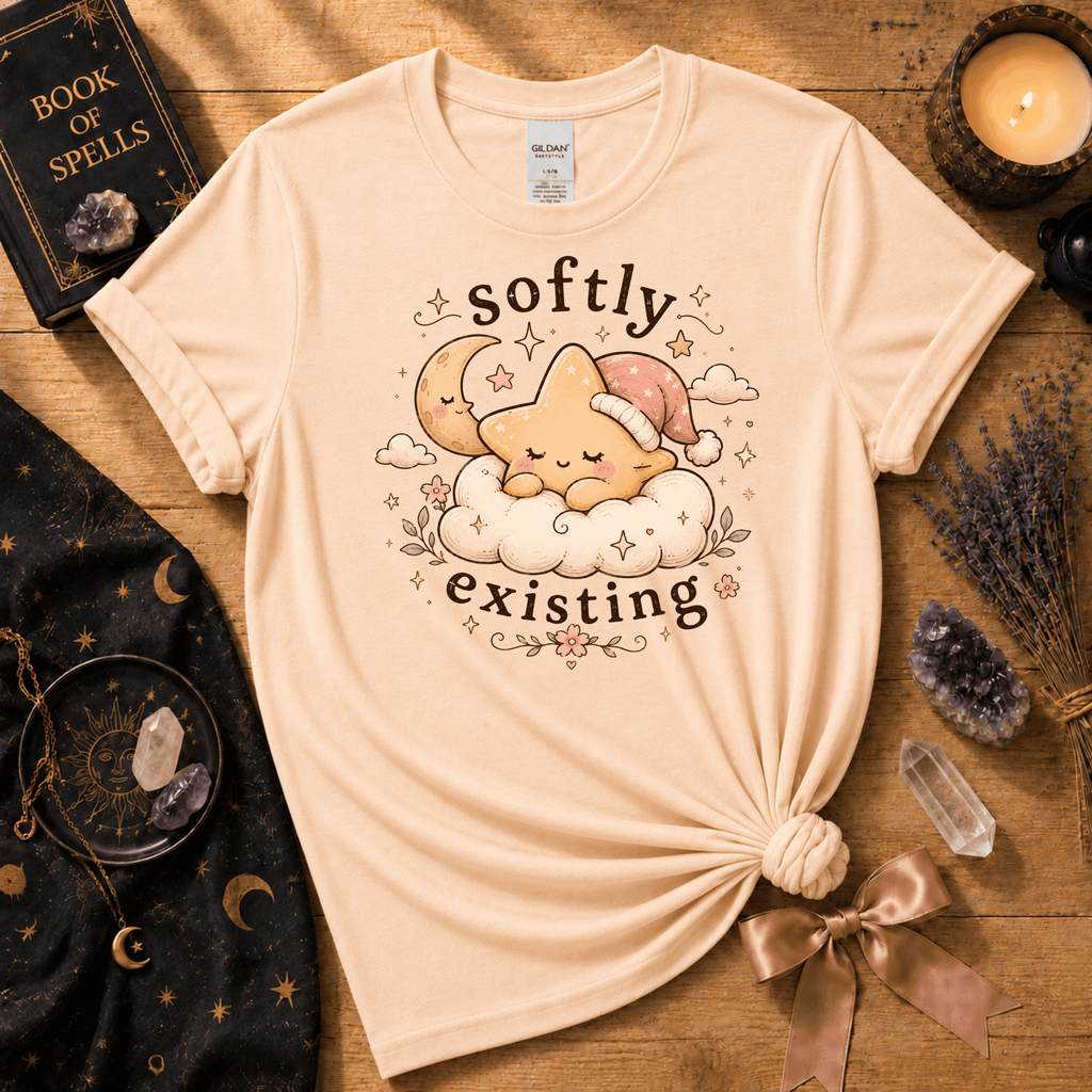 Softly Existing celestial graphic t-shirt displayed in a cozy flat lay in natural.