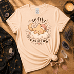 Softly Existing celestial graphic t-shirt displayed in a cozy flat lay in natural.