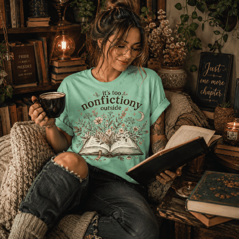 Woman reading a book and holding a mug, wearing the Nonfictiony Premium T-Shirt in mint