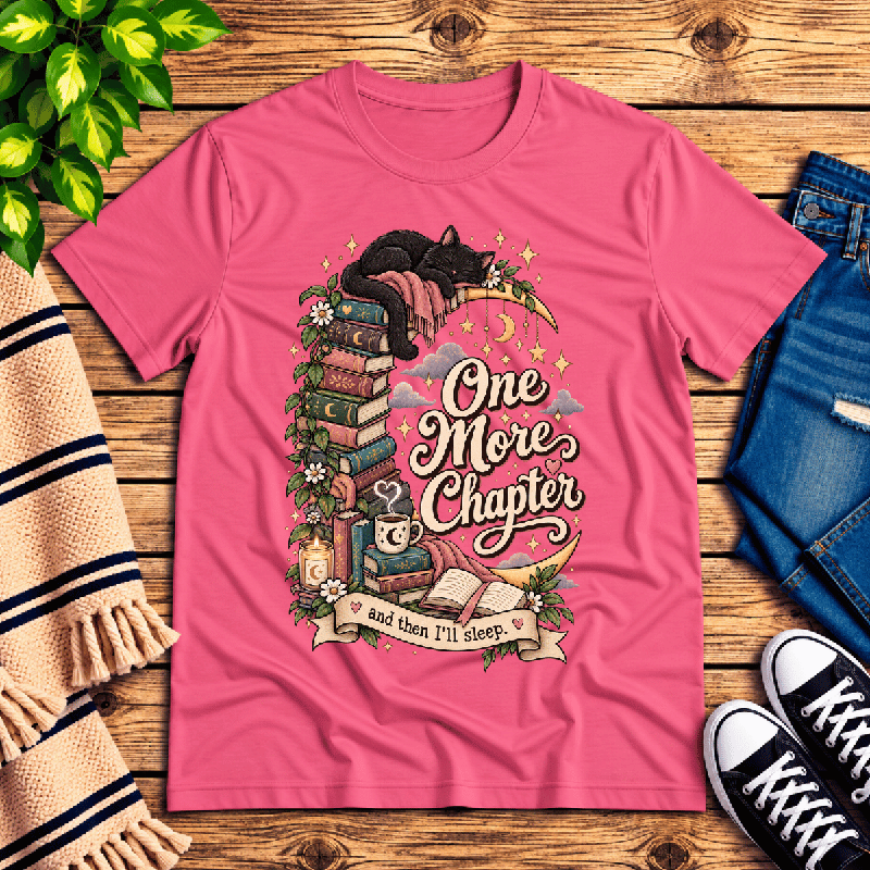 One More Chapter Premium T-Shirt in charity pink, flat lay with black cat on a crescent moon and stacked books graphic