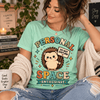 Woman seated wearing a cardigan, wearing the Personal Space Enthusiast Premium T-Shirt in mint