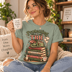 Woman holding a mug, wearing the Protecting My TBR Premium T-Shirt in sage