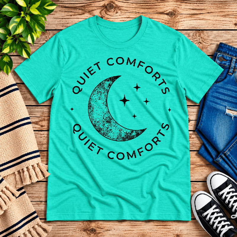 Quiet Comforts Dark Premium T-Shirt in heather sea green, flat lay with crescent moon and "Quiet Comforts" circular text graphic
