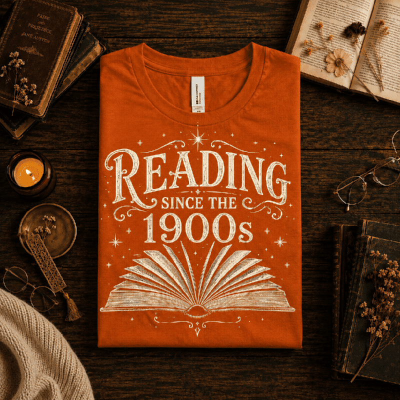 Reading Since Premium T-Shirt in burnt orange, folded close-up styled with books, a candle, and glasses