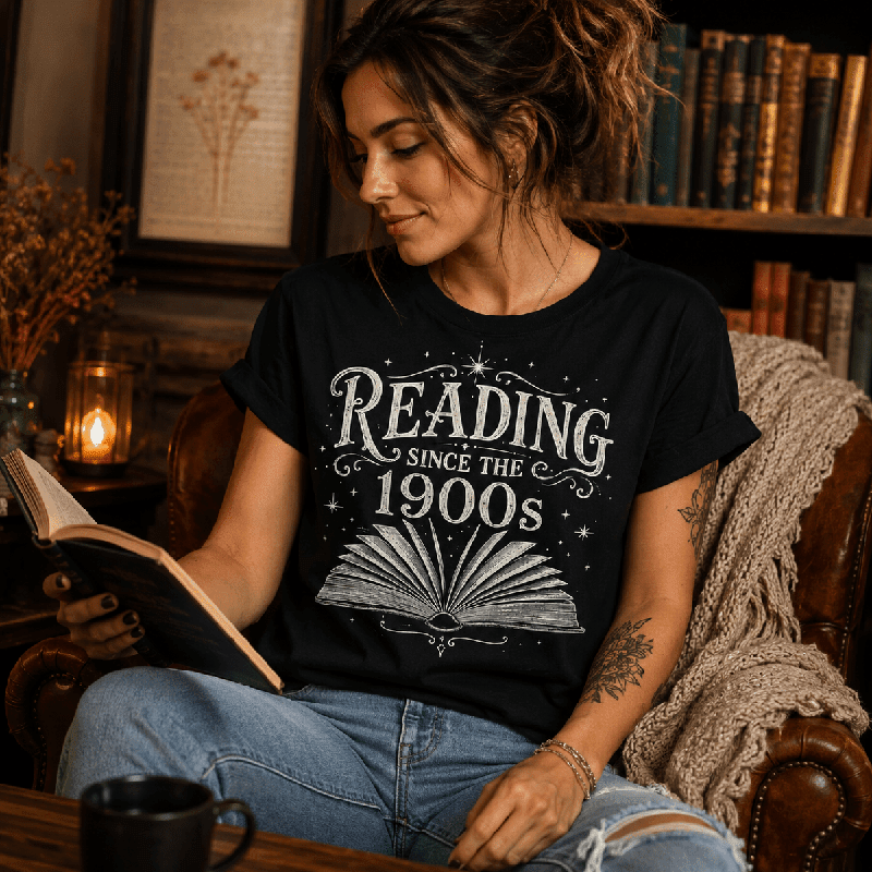 Woman reading a book in a chair, wearing the Reading Since Premium T-Shirt in vintage black