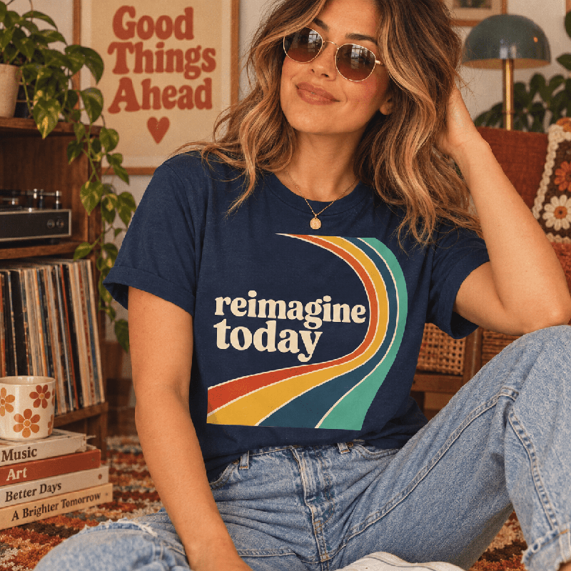 Woman seated indoors, wearing the Reimagine Today Premium T-Shirt in navy