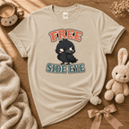 Free Side Eye cute animal graphic t-shirt displayed in a cozy flat lay in sand.