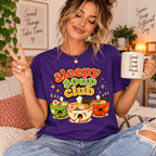 Woman holding a "Good Soup Good Mood" mug, wearing the Sleepy Soup Club Premium T-Shirt in team purple