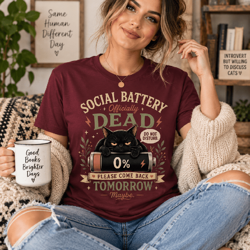 Woman holding a mug, wearing the Social Battery Dead Premium T-Shirt in maroon