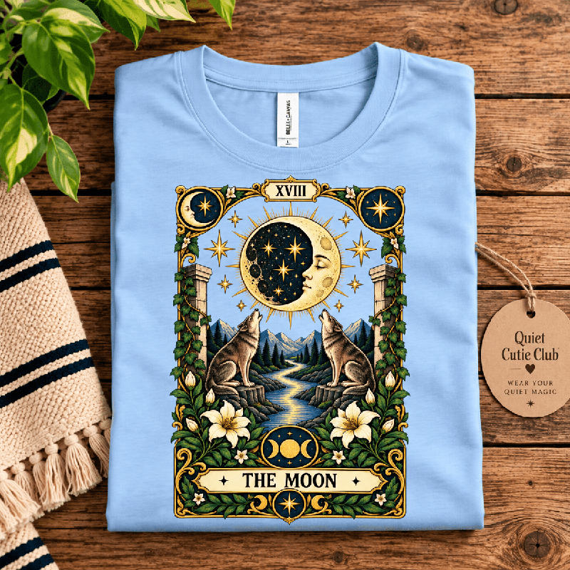 The Moon Premium T-Shirt in baby blue, folded close-up with neck tag showing