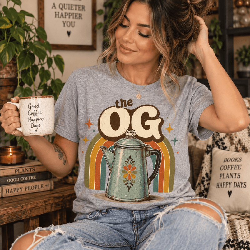 Woman holding a mug, wearing the OG Premium T-Shirt in athletic heather gray